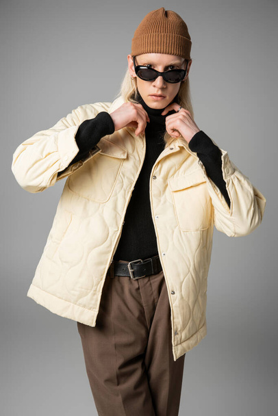 modelo joven no binario en chaqueta de invierno tocando cuello de cuello alto negro, concepto de moda - Foto, Imagen