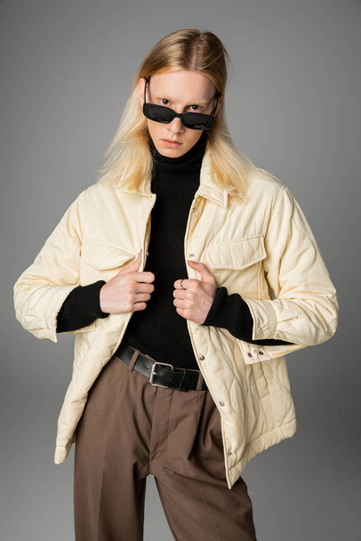 вертикальный снимок молодого привлекательного андрогинного человека в зимнем модном наряде, смотрящего в камеру - Фото, изображение