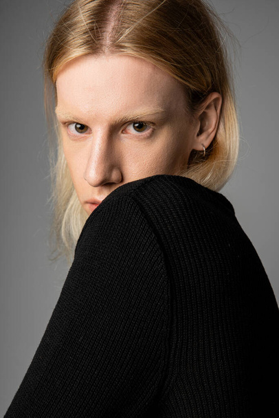 vertical shot of appealing non binary model in black turtleneck with long hair looking at camera - Photo, Image