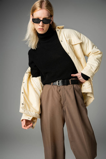 вертикальный снимок молодой красивой андрогинной модели в модном наряде, смотрящей в камеру, моду - Фото, изображение