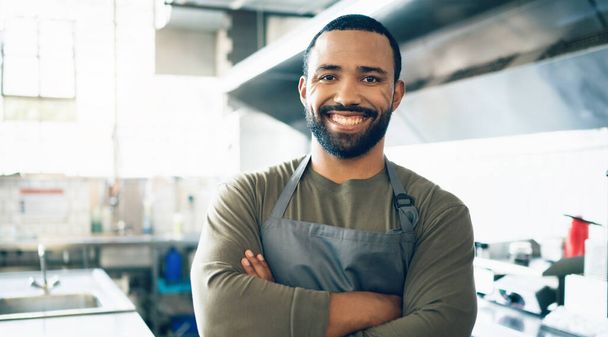 Happy man, gezicht en kleine ondernemer in keuken in restaurant voor horeca, koken of eten. Portret van mannelijke persoon, werknemer of ober glimlach in vertrouwen voor professionele carrière. - Foto, afbeelding