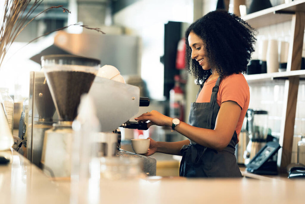 Happy woman, barista and small business owner at cafe for service, coffee or beverage by counter at store. Female person, employee or waiter making espresso, cappuccino or latte at restaurant or shop. - Photo, Image