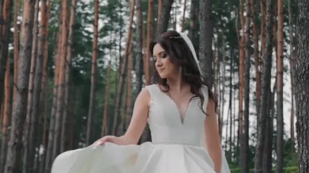 Krásná nevěsta tančí poblíž lesa, točí se kolem sebe v bílých šatech. - Záběry, video