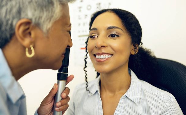 Женщина, уход за глазами и медицинский тест с офтальмоскопом для проверки глаукомы, глазных консультаций и оценки здоровья. Клинический оптик, анализ зрения и сетчатки глаза счастливого пациента с инструментами для линз. - Фото, изображение
