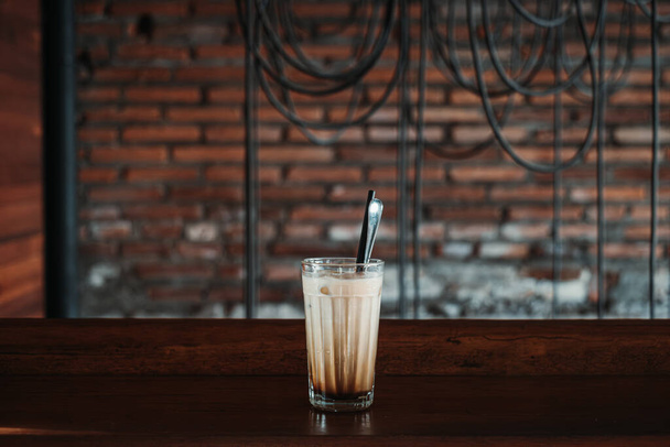 Un verre de café latte avec cuillère en acier inoxydable et paille dans un café rustique vintage. Minimalisme. Concept. - Photo, image