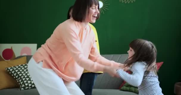Joyful Caucasian family, including the mother, son, and daughter, come together to dance. Their smiles and synchronized movements create a heartwarming scene of familial happiness. - Footage, Video