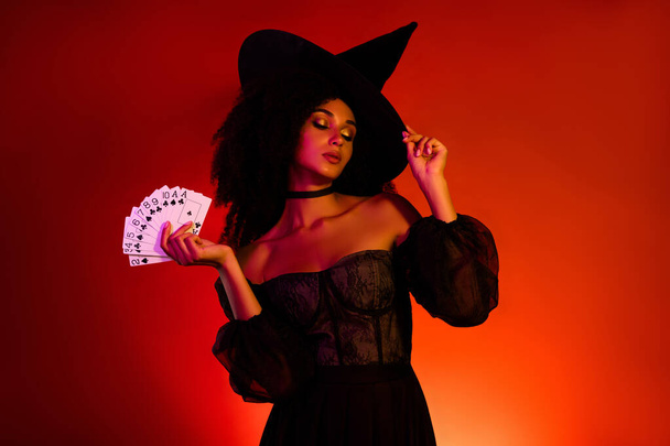 Prachtige dame betoverde mensen op Halloween nacht doen donkere betovering met poker speelkaarten over rode achtergrond. - Foto, afbeelding