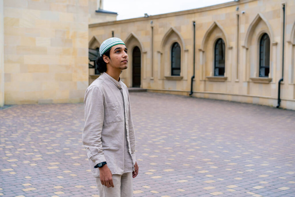 Egy fiatal arab férfi belép egy muzulmán mecset udvarára, és lelkesen nézi az építészetet. - Fotó, kép