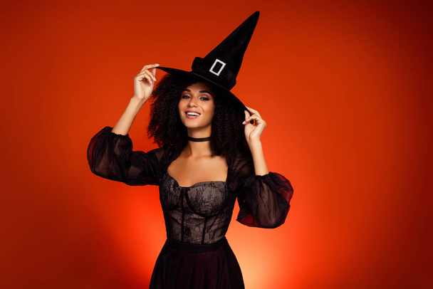 Fotografie krásné ohromující čarodějnice připravit na halloween sabbath upravit její har přes červenou barvu pozadí. - Fotografie, Obrázek