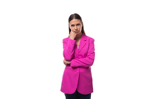 mladý chytrý kancelář pracovník žena s černými vlasy oblečený v růžové bundě stojí zamyšleně. - Fotografie, Obrázek