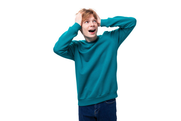 Красивый рыжий молодой человек в голубом свитере преподносит сюрприз. - Фото, изображение