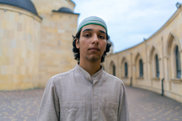 retrato de un joven árabe mirando a la cámara sobre el fondo de una mezquita musulmana - Foto, imagen