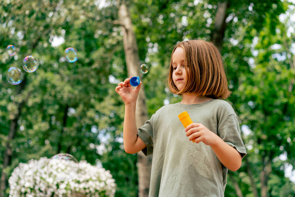 portret mooi schattig klein meisje blazen zeep zeepbel in stadspark gelukkig zorgeloos jeugd - Foto, afbeelding