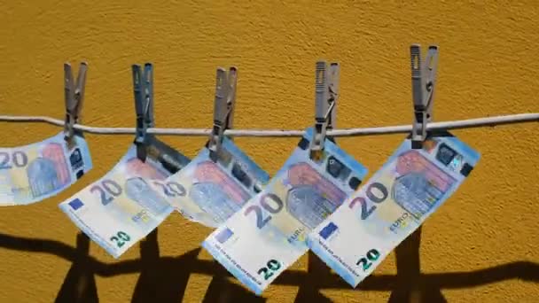 Eurobankovky visící na provaze na špendlíkách a třepotání. Peníze se houpají ve větru na pozadí žluté zdi. Pojetí praní špinavých peněz. - Záběry, video