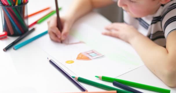 Netter Junge, der zu Hause oder im Klassenzimmer mit Buntstiften auf einem Blatt Papier zeichnet. Kind lernt durch Zeichnen. Bildungskonzept. Hochwertiges 4k Filmmaterial - Filmmaterial, Video