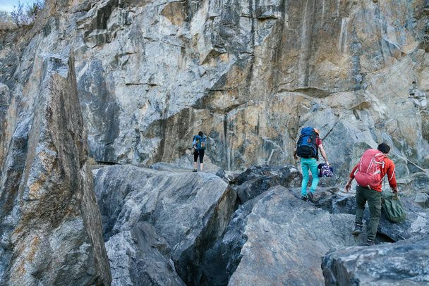 Climbers preparing for ascent. Three male female persons walking on the rocks. Extreme outdoor sport. - Photo, Image