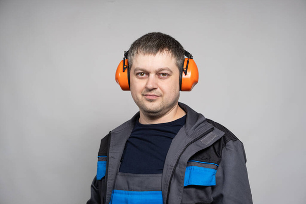 Portrait of a man in earmuffs and overalls on a white background - Photo, Image