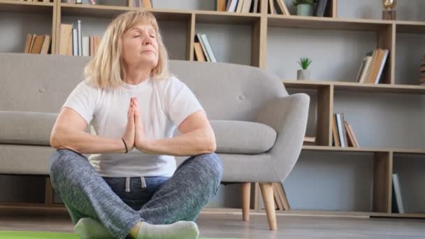 Bella nonna che fa esercizi di yoga a casa. Formazione di yoga per anziani. Concetto yoga. - Filmati, video