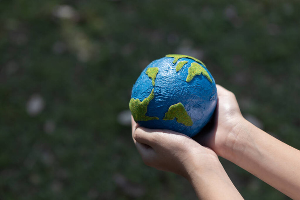 Young boys hand holding planet Earth globe at natural park background as Earth day to save this planet with ESG principle and environment friendly energy for brighter future. Gyre - Photo, Image