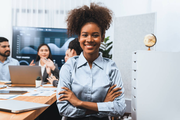 Porträt einer glücklichen jungen afrikanischen Geschäftsfrau mit einer Gruppe Büroangestellter bei einem Treffen mit einem Bildschirm im Hintergrund. Selbstbewusste Bürokauffrau bei Teamsitzung. Eintracht - Foto, Bild