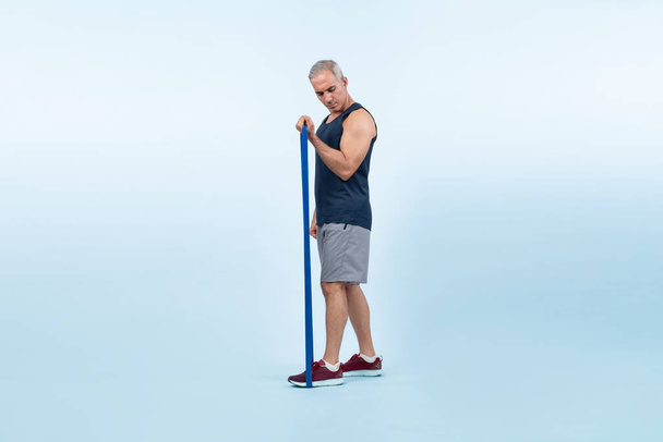 Celotělová délka záběr atletický a sportovní senior muž s fitness odolnost pásmo na izolovaném pozadí. Zdravý aktivní tělo a péče o tělo životní styl po odchodu do důchodu. Clovek - Fotografie, Obrázek