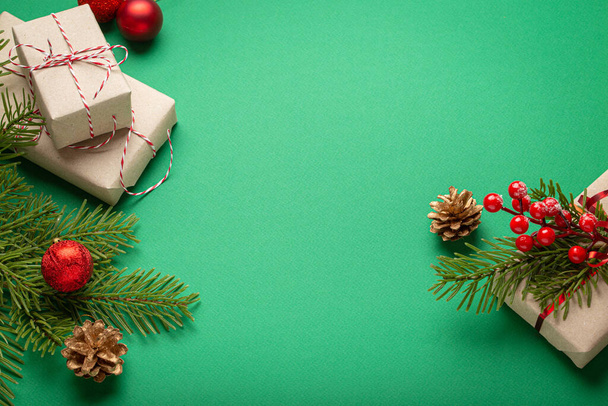 Boże Narodzenie lub Nowy Rok święto zielony papier świąteczne tło z ozdobą jodły, pudełka, szyszki, jagody, błyszczące czerwone kulki. Miejsce na tekst.. - Zdjęcie, obraz
