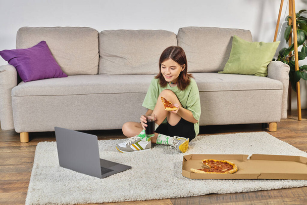 concentrée adolescente avec pizza et soda regarder film sur ordinateur portable sur le sol dans le salon, loisirs - Photo, image