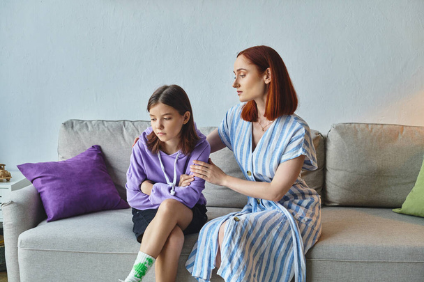 zorgzame moeder kalmerende boos tienerdochter zitten op de bank in de woonkamer, zorg en ondersteuning - Foto, afbeelding