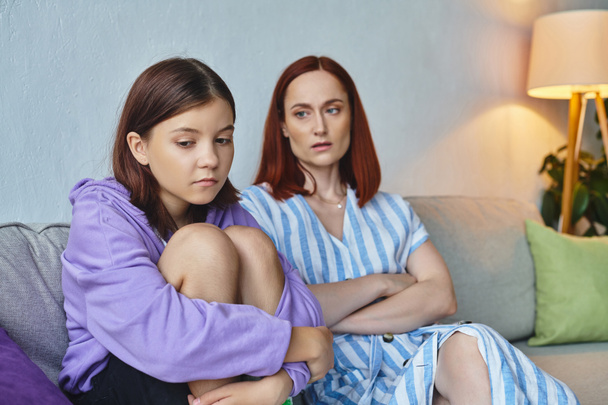 ανήσυχη μητέρα κοιτάζοντας κατάθλιψη έφηβος κόρη στον καναπέ στο σαλόνι, υποστηρικτική γονέα - Φωτογραφία, εικόνα
