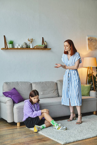donna seria che parla con frustrata figlia adolescente seduta sul pavimento in soggiorno, divario generazionale - Foto, immagini