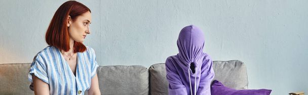 беспокойная женщина разговаривает с расстроенной дочерью скрывая лицо с капюшоном на диване в гостиной, баннер - Фото, изображение