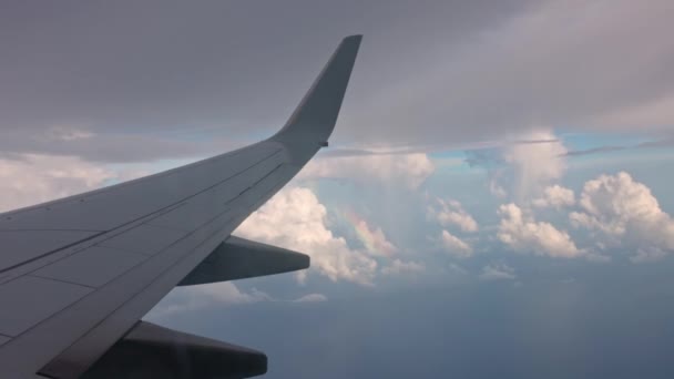 Regenbogen am wolkenverhangenen blauen Himmel unter Tragflächen fliegender Flugzeuge. - Filmmaterial, Video
