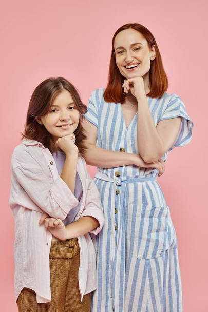 cheerful mother and preteen daughter in stylish casual clothes posing and smiling at camera on pink - Photo, Image
