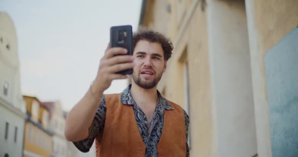 Молодий чоловік впливає на запис відео через мобільний телефон під час ходьби в місті - Кадри, відео