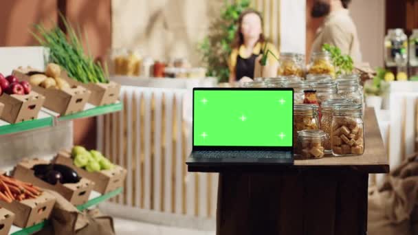 Laptop z kluczem Chroma z przestrzenią do kopiowania używaną jako znak handlowy w zrównoważonym sklepie lokalnym. Reklama promocyjna na urządzeniu z zielonym ekranem w sklepie spożywczym z produktami w opakowaniu ze szklanym słoikiem wielokrotnego użytku - Materiał filmowy, wideo