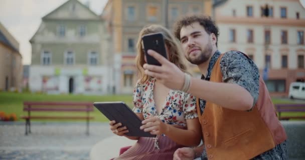 Fiatal férfi csinál szelfi barátnő a mobiltelefon, miközben ül a parkban hétvégén - Felvétel, videó