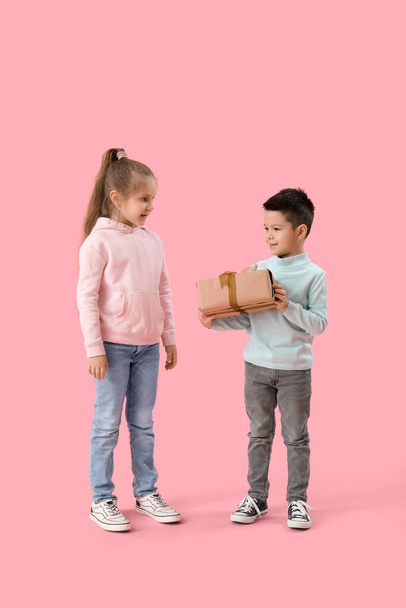 Cute little children in sweaters with gift on pink background - Photo, Image