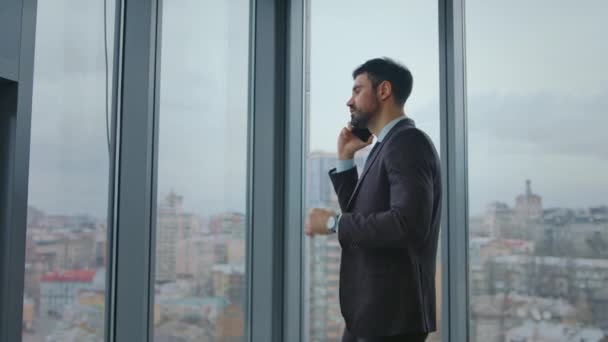 Ofis panoramik penceresinde duran iş adamı telefon görüşmeleri hakkında konuşuyor. Güvenilir sakallı yönetici iş görüşmesinde ortaklarla konuşuyor. Ciddi bir adam telefonda işi tartışıyor.. - Video, Çekim