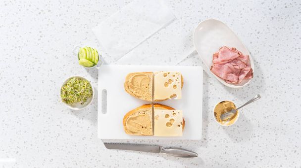 Ležel. Montáž šunky, okurky a klíčkových sendvičů na bílou řezací desku. - Fotografie, Obrázek