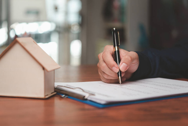 Homme d'affaires signant un contrat pour l'achat d'une maison ou d'un agent immobilier. Investissement et prêt bancaire ou assurance habitation. - Photo, image