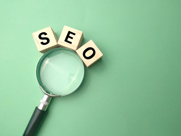 Top view magnifying glass and wooden cube with the word SEO. Business concept. - Photo, Image