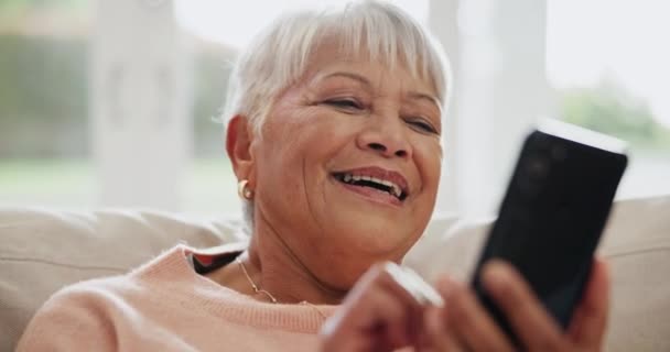 Starsza kobieta, smartfon i śmiech na portalach społecznościowych, kanapie w salonie i memach. Emerytowany, szczęśliwy i cieszący się emeryturą na relaks, aplikacja mobilna i SMS-y do tworzenia sieci, transmisji na żywo i połączenia. - Materiał filmowy, wideo