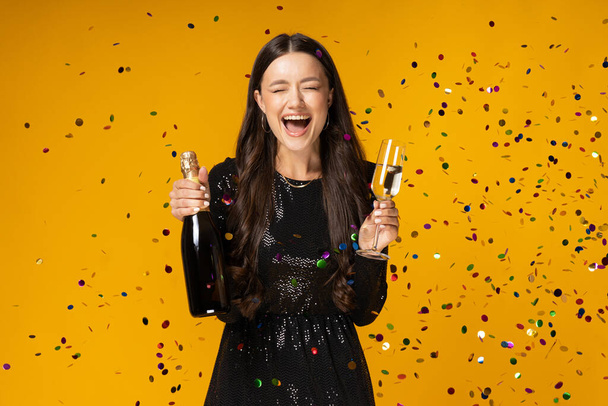 Girl with champagne and glasses on a yellow background. - Photo, Image