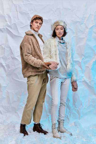 trendi férfi gazdaság kezét ázsiai nő kesztyűben álló hó fehér texturált háttér - Fotó, kép