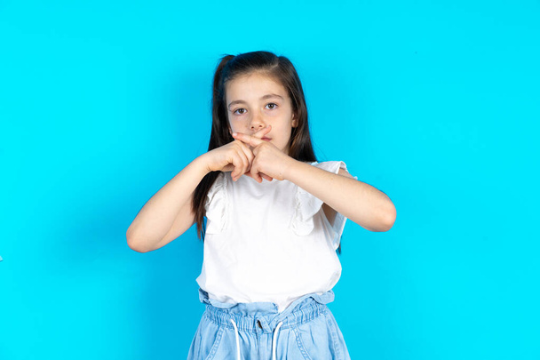 Beautiful caucasian kid girl standing over blue studio background Has rejection angry expression crossing fingers doing negative sign. - Photo, Image