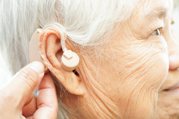 Lékař nainstalovat naslouchátko na starší pacient ucho ke snížení ztráty sluchu. - Fotografie, Obrázek