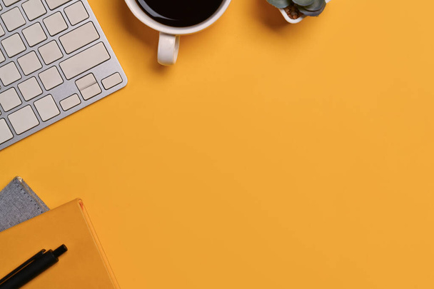 Ένα φλιτζάνι καφέ, πληκτρολόγιο και σημειωματάριο σε κίτρινο φόντο. Διάστημα για κείμενο διαφημιστικού μηνύματος. - Φωτογραφία, εικόνα