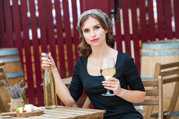 Hermosa joven bebiendo vino blanco en la terraza de un restaurante. Relajante después del trabajo con una copa de vino. Mujer soltera divirtiéndose. - Foto, Imagen