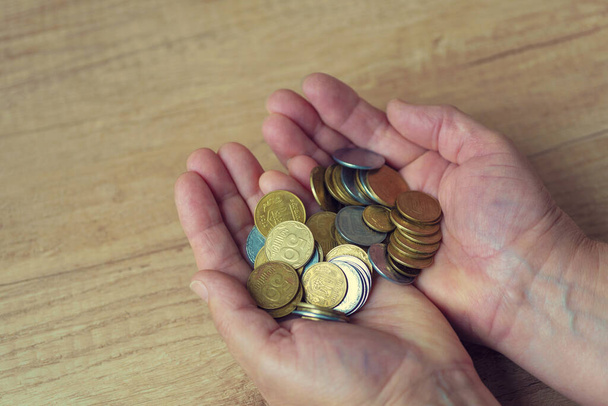 Монети в долонях. Гроші в руці. Концепція бідності, дефіцит готівки. На монеті написано українською - 50, 25 і 5 копій. - Фото, зображення