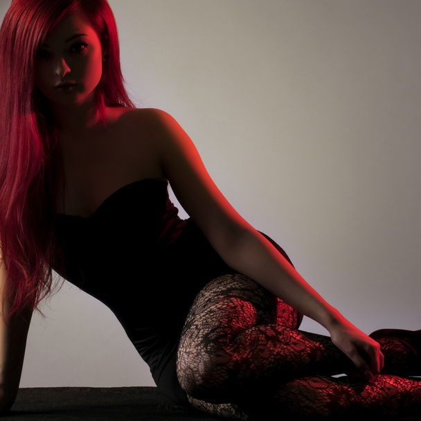 Bella donna dai capelli rossi in posa su zoccolo su sfondo grigio
 - Foto, immagini